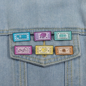 Macro view of six colorful stamp-shaped enamel pins on light blue denim fabric