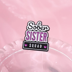 Pink Sober Sister Squad enamel pin brooch with purple hearts and black lettering