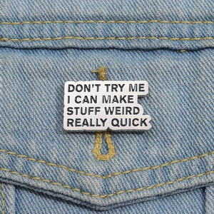 Close-up of vintage metal brooch with funny quote on denim jacket texture