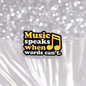 Enamel music brooch with 'Music speaks when words can't' quote on white textured background