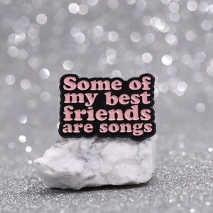 Black enamel pin with pink text 'Some of my best friends are songs' for music lovers