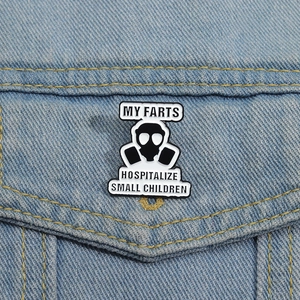 Detail of gas mask enamel pin with funny text on blue denim jacket pocket