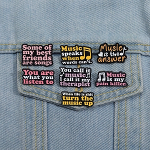 Set of 7 colorful music-themed enamel pins pinned on a blue denim jacket pocket