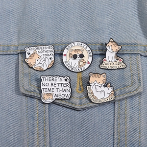 Detail of five cute cartoon cat enamel pins pinned on a blue denim jacket pocket