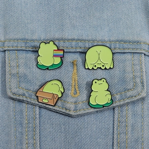 Set of four cute green frog enamel pins on denim jacket showing diverse funny poses