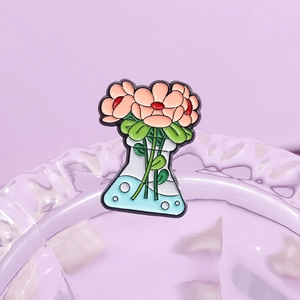 Spilla smaltata con pallone da laboratorio e fiori su sfondo viola estetico elegante