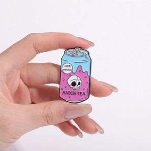 Détail d'un pin's en émail en forme de canette avec crâne et texte ANXIETEA rigolo