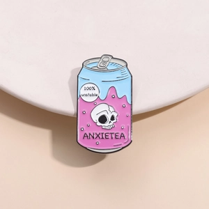Détail macro du pin's émaillé canette avec motif crâne et texte ANXIETEA sur support