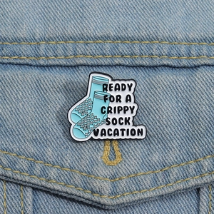Detailed close-up of a blue enamel pin on denim with Grippy Sock Vacation text