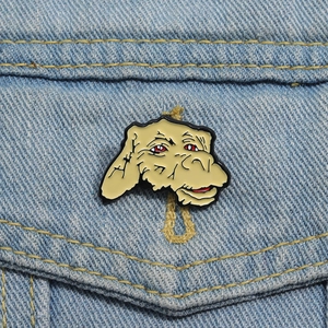Detailed close-up of a cartoon alien enamel pin on a denim jacket pocket