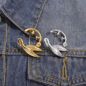 Detail von silbernen und goldenen Schwalben-Broschen aus Metall an einer Jeansjacke