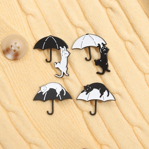 Artistic cat and umbrella enamel pins set in black and white on knit fabric