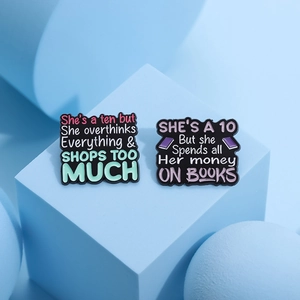 Farbenfrohe Emaille-Pins mit lustigen Sprüchen auf pastellblauen geometrischen Ständern