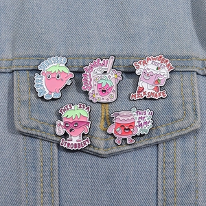 Detailed view of five strawberry enamel pins styled on a blue denim jacket pocket