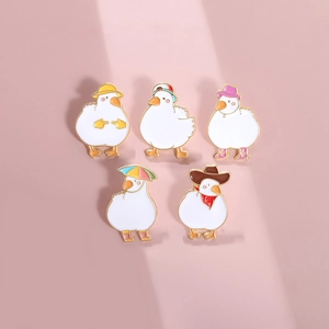 Set of five cute white duck enamel pins with colorful hats and boots on pink background
