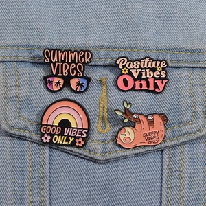 Détail de quatre pins en émail colorés avec paresseux et arc-en-ciel sur une veste