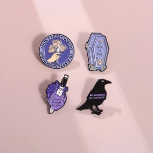 Detail of four gothic enamel pins featuring a crow, coffin, and dagger motifs in purple and black