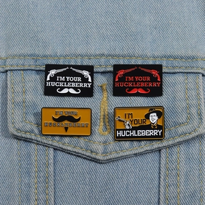 Detail of four western enamel pins with 'I'M YOUR HUCKLEBERRY' quote on denim jacket