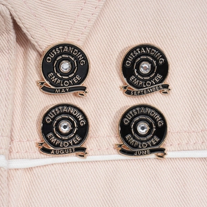 Macro view of gold and black enamel Outstanding Employee pins on pink denim fabric