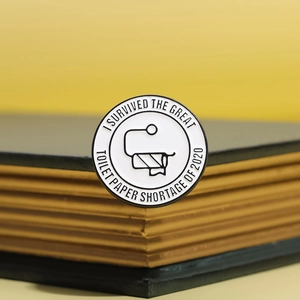 Round enamel toilet paper shortage badge displayed on vintage books with yellow background