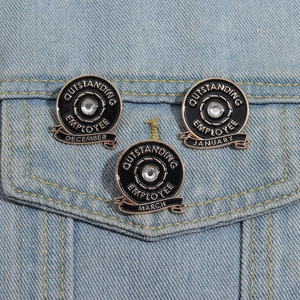 Macro detail of three Outstanding Employee enamel pins on a denim jacket pocket