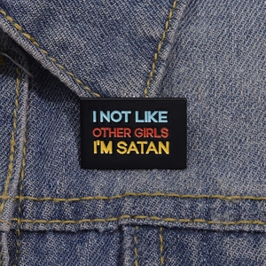 Funny rectangular black enamel brooch with colorful I'M SATAN text on denim jacket