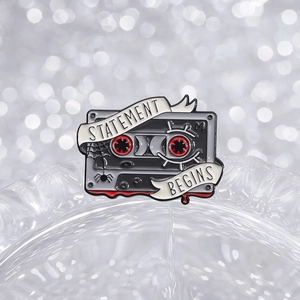 Gothic green cassette enamel pin with spider web design and Statement Begins text