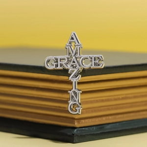 Silver punk style cross brooch with Amazing Grace lettering on vintage book background