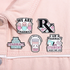 Detail of five medical enamel pins on pink denim, featuring pills and Rx pharmacy designs