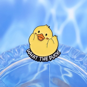 Cute cartoon yellow enamel duck pin badge with What The Duck text on blue water background