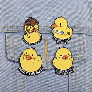 Detail of four yellow duck enamel pins with humorous text on blue denim fabric
