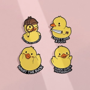 Set of four cute yellow duck enamel pins with humorous text on a pink background