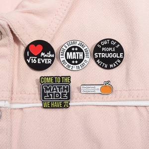 Detailed view of five math-themed enamel pins pinned on a pink denim fabric jacket