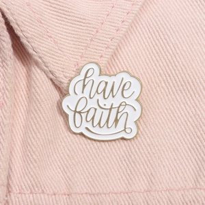 Inspirational 'have faith' enamel pin with gold metal outlines on pink denim background