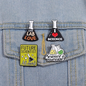 Set di 4 spille smaltate a tema laboratorio con becher e provette su giacca di jeans