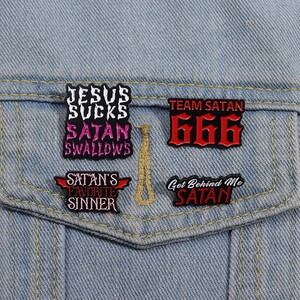 Detail of four punk enamel pins with Satanic text motifs on blue denim jacket