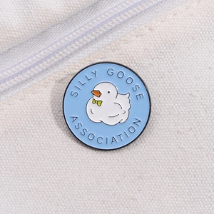 Round blue enamel pin with a cute white cartoon goose and Silly Goose Association text