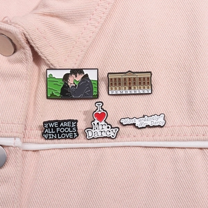 Dettaglio di cinque spille smaltate Orgoglio e Pregiudizio su colletto di jeans rosa