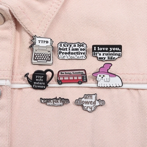 Gros plan de pin's en émail TTPD fixés sur une veste en jean rose pastel