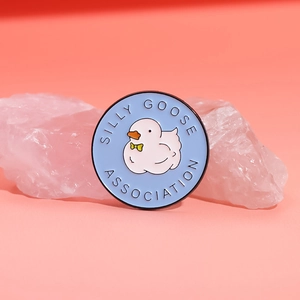 Round blue enamel pin featuring a cartoon white goose and Silly Goose Association text