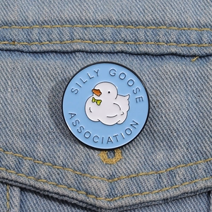 Detail of Silly Goose Association blue enamel pin badge on denim fabric background