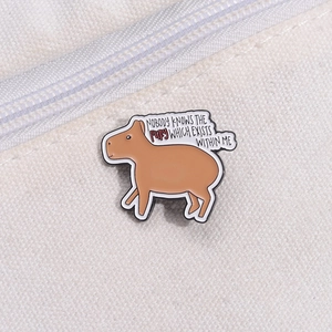 Detailed close-up of funny enamel capybara pin with comic bubble on canvas bag texture