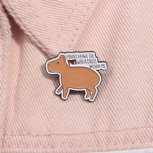 Detail of a brown capybara enamel pin on pink denim with 'Nobody knows the fury' text