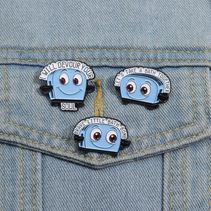 Three funny blue toaster enamel pins with dark humor text on light blue denim jacket