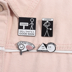 Makro-Detail von vier lustigen Emaille-Pins mit Strichmännchen auf rosa Denim