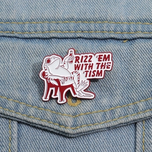Macro detail of enamel frog pin with RIZZ EM WITH THE TISM text on blue denim