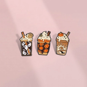 Three Halloween enamel pins featuring orange pumpkin drinks and ghosts on pink background
