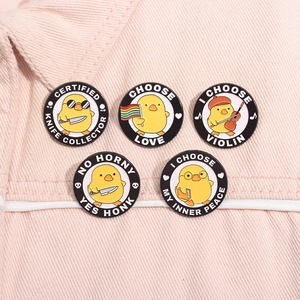Detail of five cute yellow duck enamel pins with humorous quotes on pink denim fabric