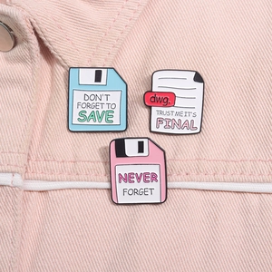 Dettaglio di spillette smaltate retro tech su denim rosa, con design a floppy e icone