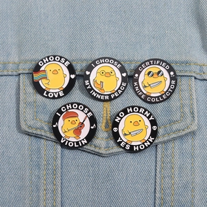 Close-up of five cartoon yellow duck enamel pins on denim jacket pocket